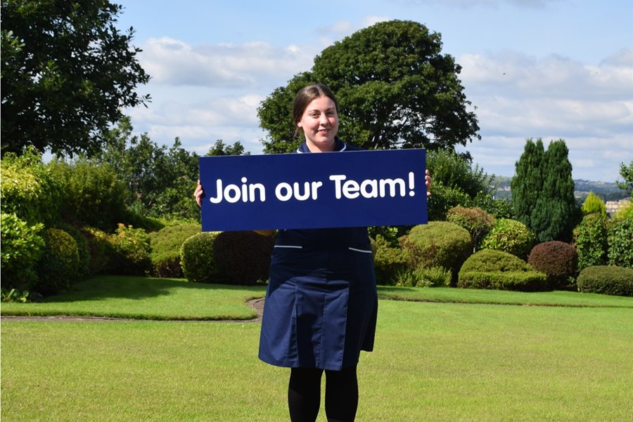 Our Senior Sister Katy holding a Join Our Team sign